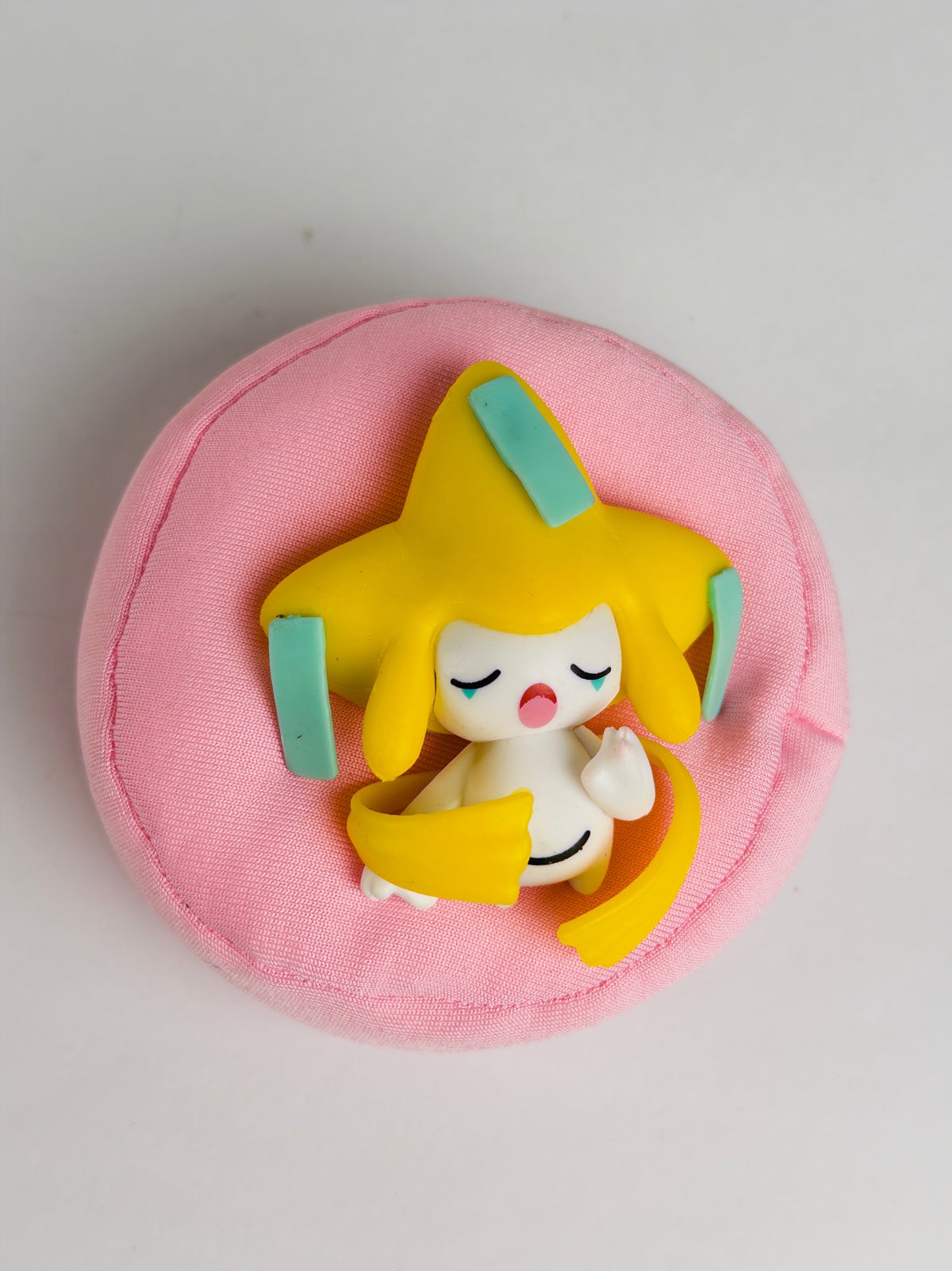 Sleeping Jirachi figure on pink plush cushion